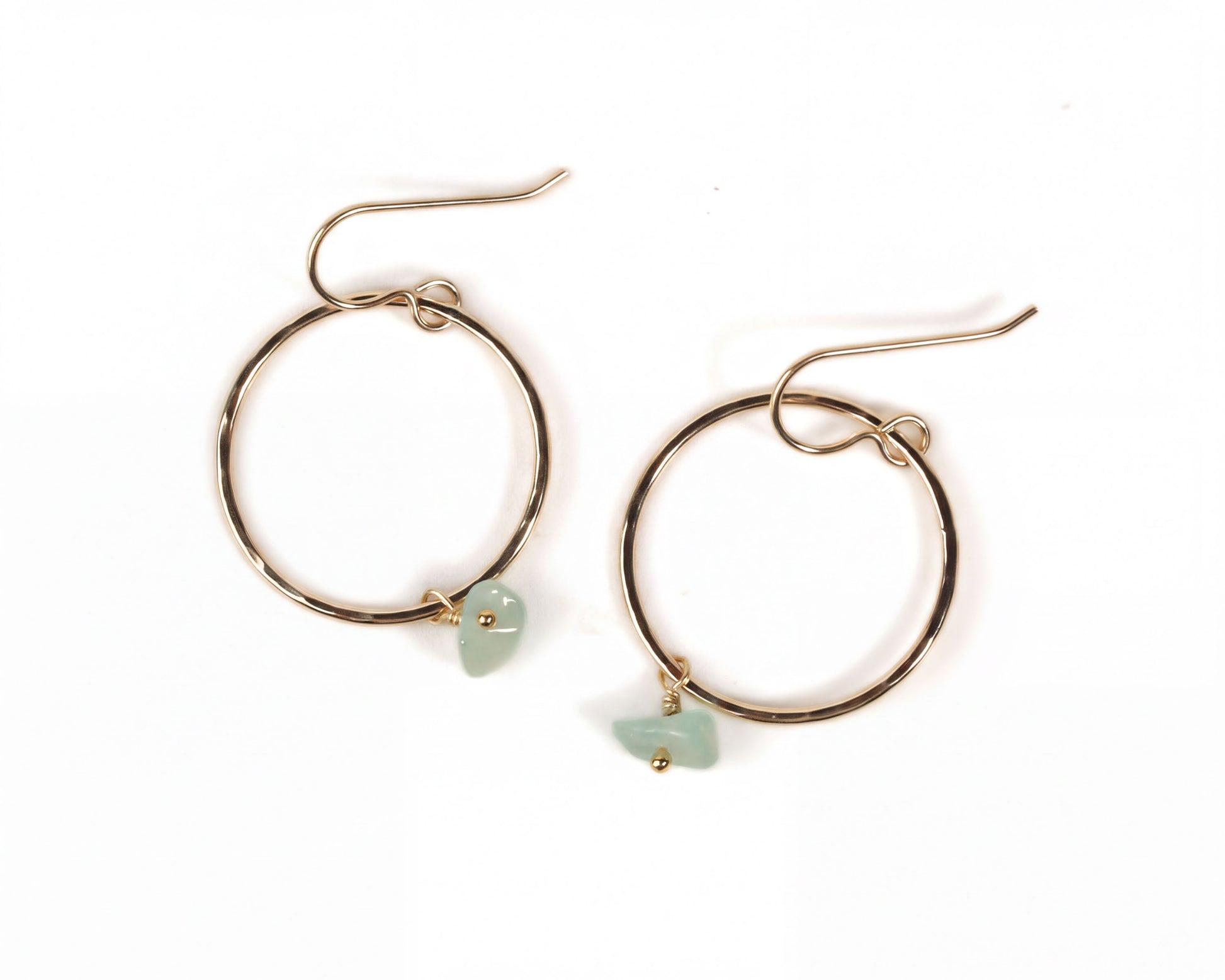 A pair of gold hoop earrings with small green stones hanging from them.