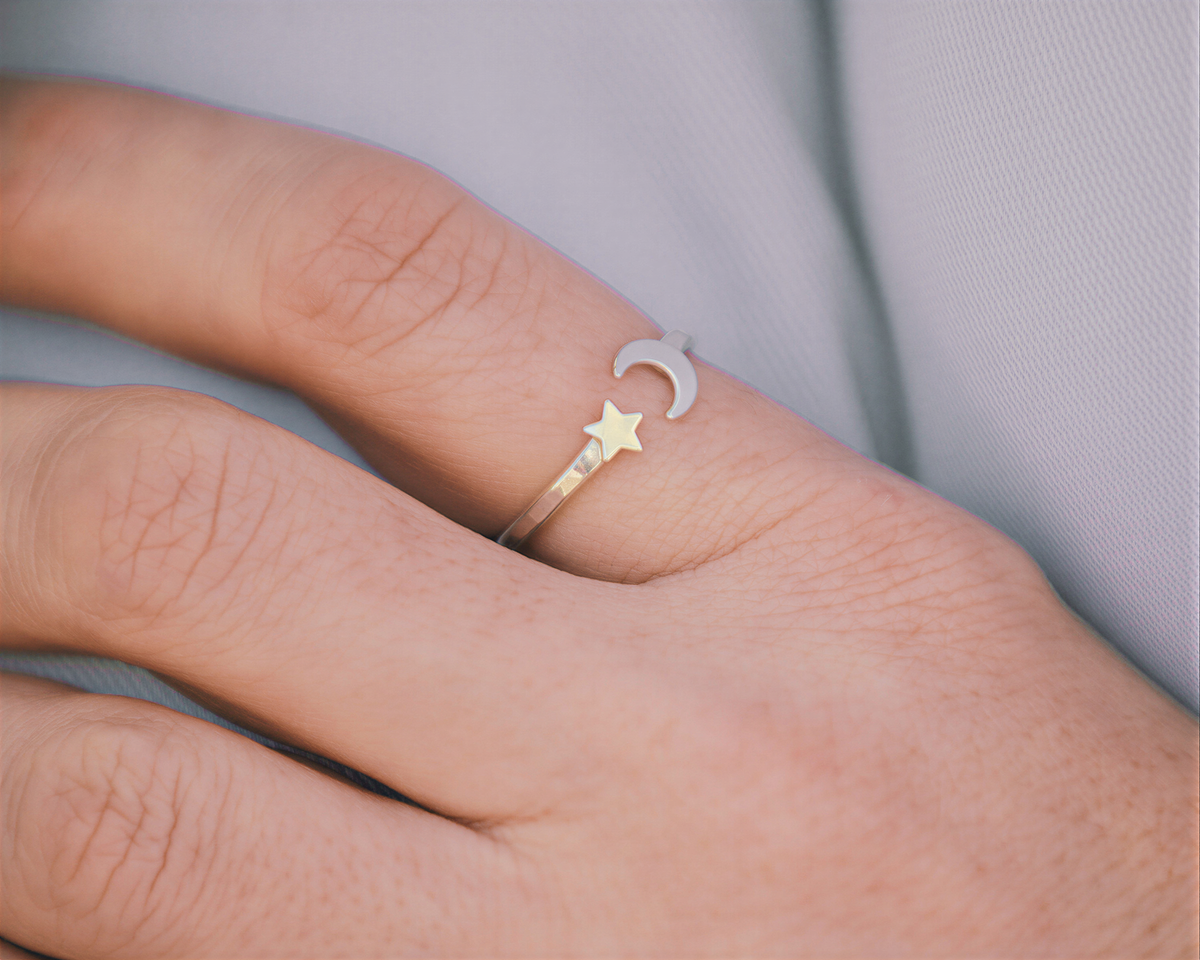 A close-up of a person's hand wearing a ring with a moon and star design.