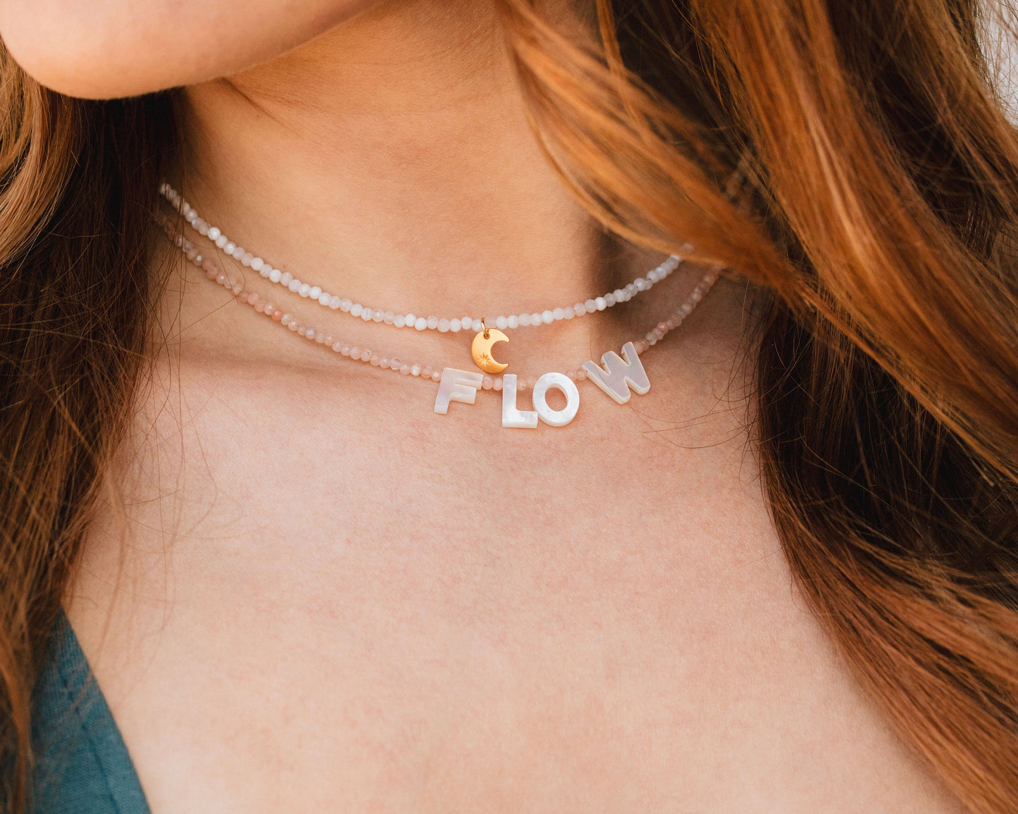 A close-up of a person's neck with a choker necklace featuring the word "FLOW" spelled out in letters.