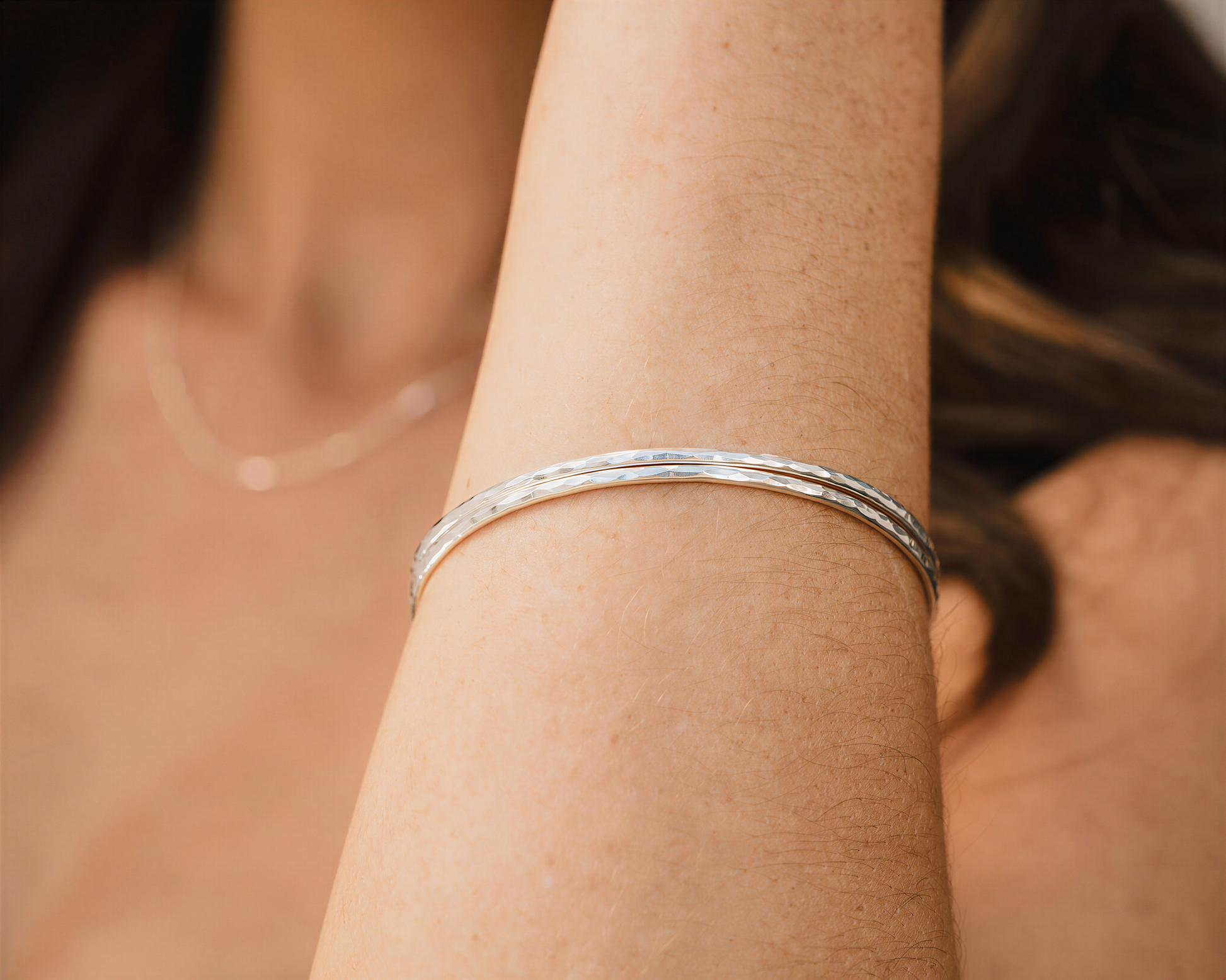 A close-up view of a person's arm wearing a silver bracelet.