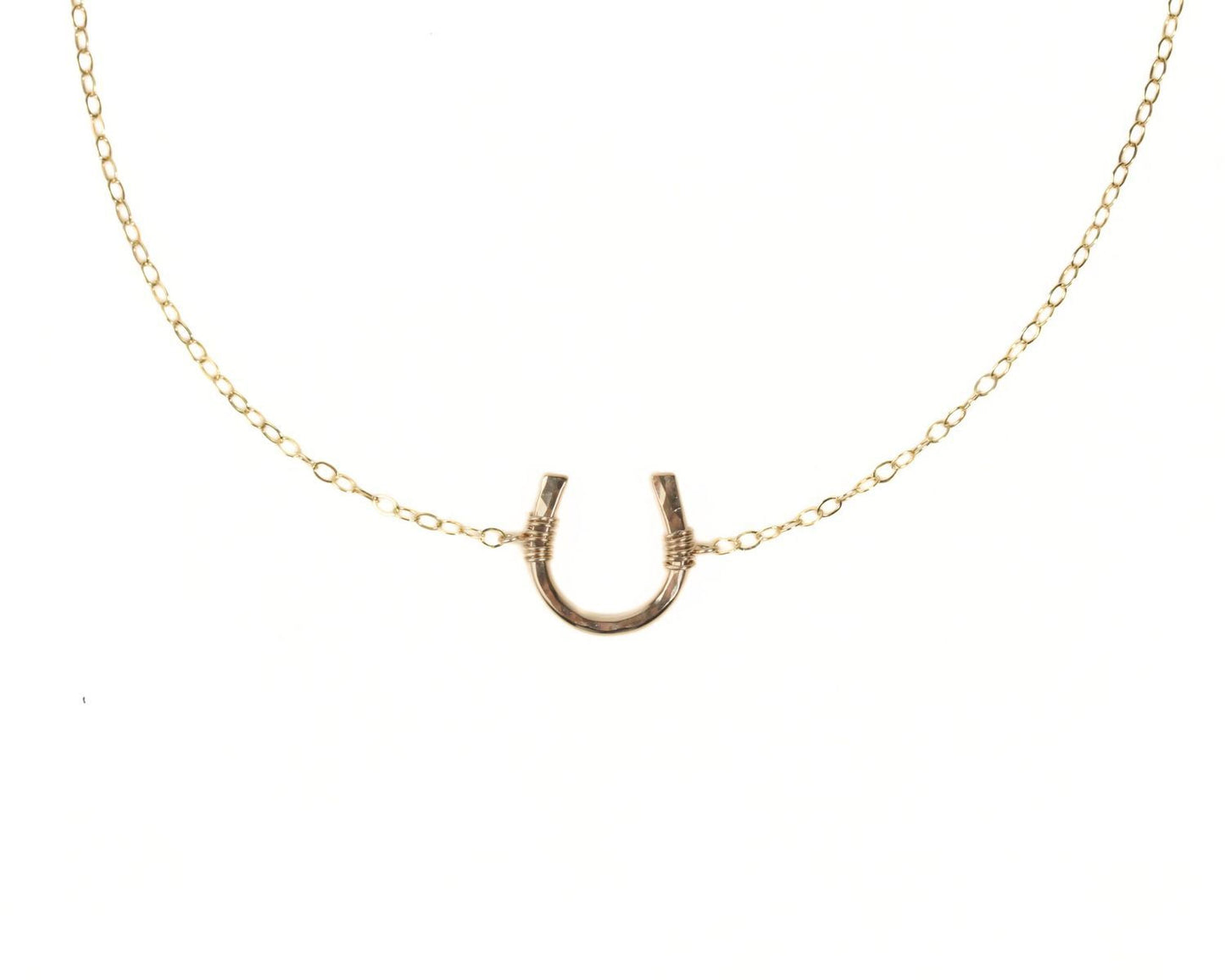 A gold-colored necklace with a horseshoe pendant.