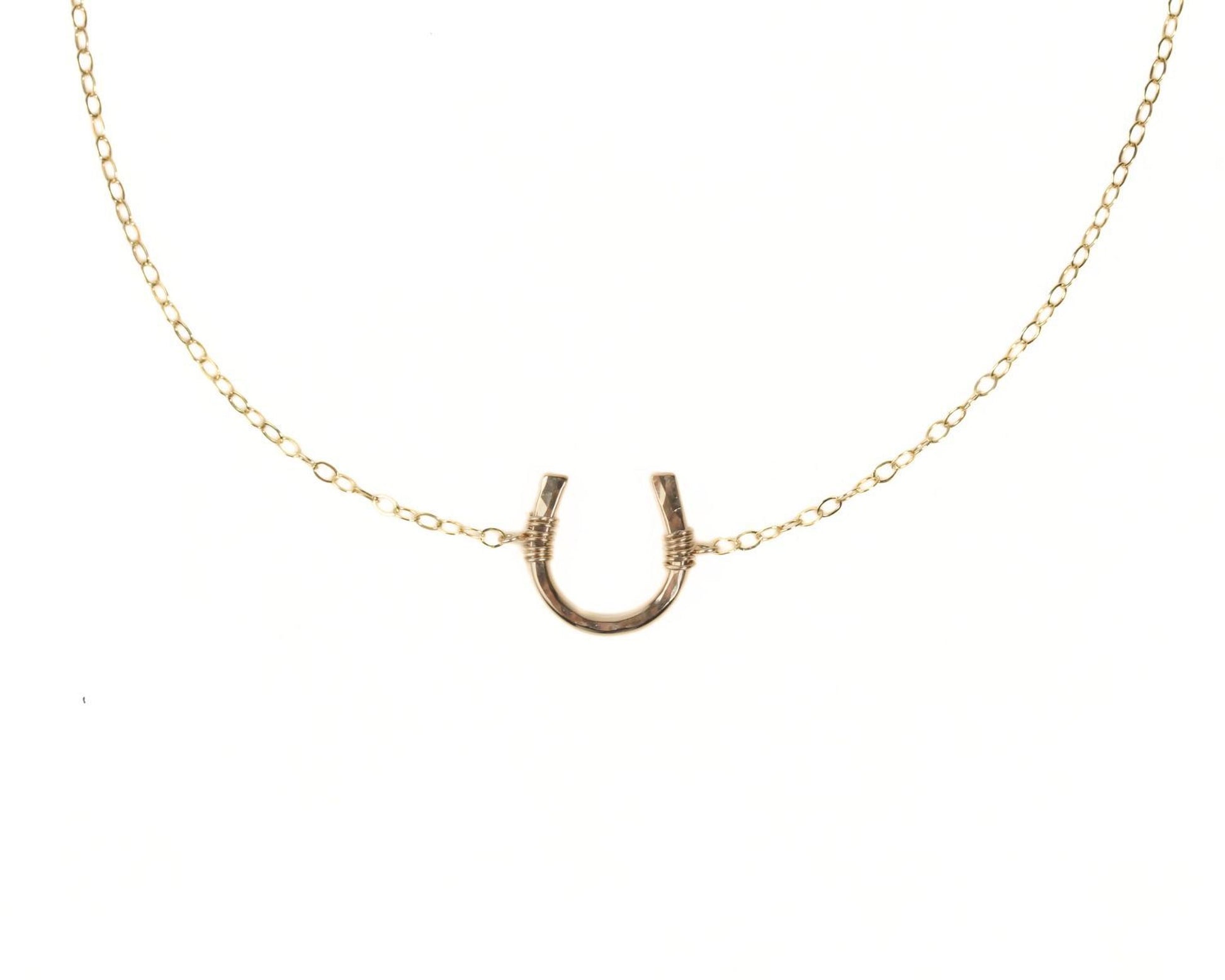 A gold-colored necklace with a horseshoe pendant.