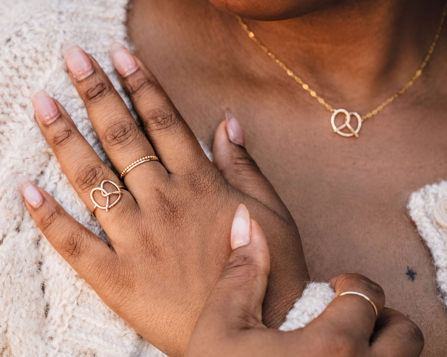A close-up of a person's hand wearing multiple rings, including a ring with a heart design and another ring with a heart-shaped charm.
