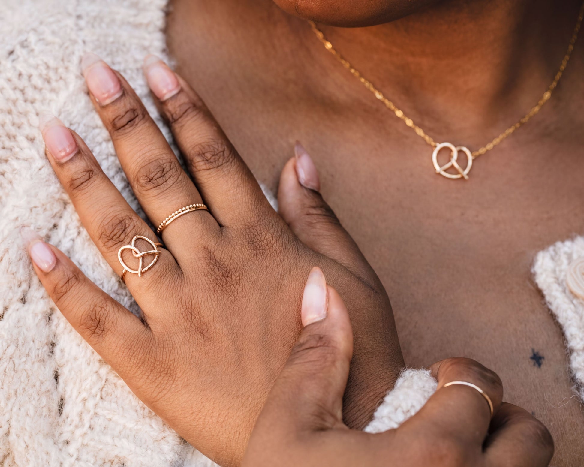 A close-up of a person's hand wearing multiple rings, including a ring with a heart design and another ring with a heart-shaped charm.