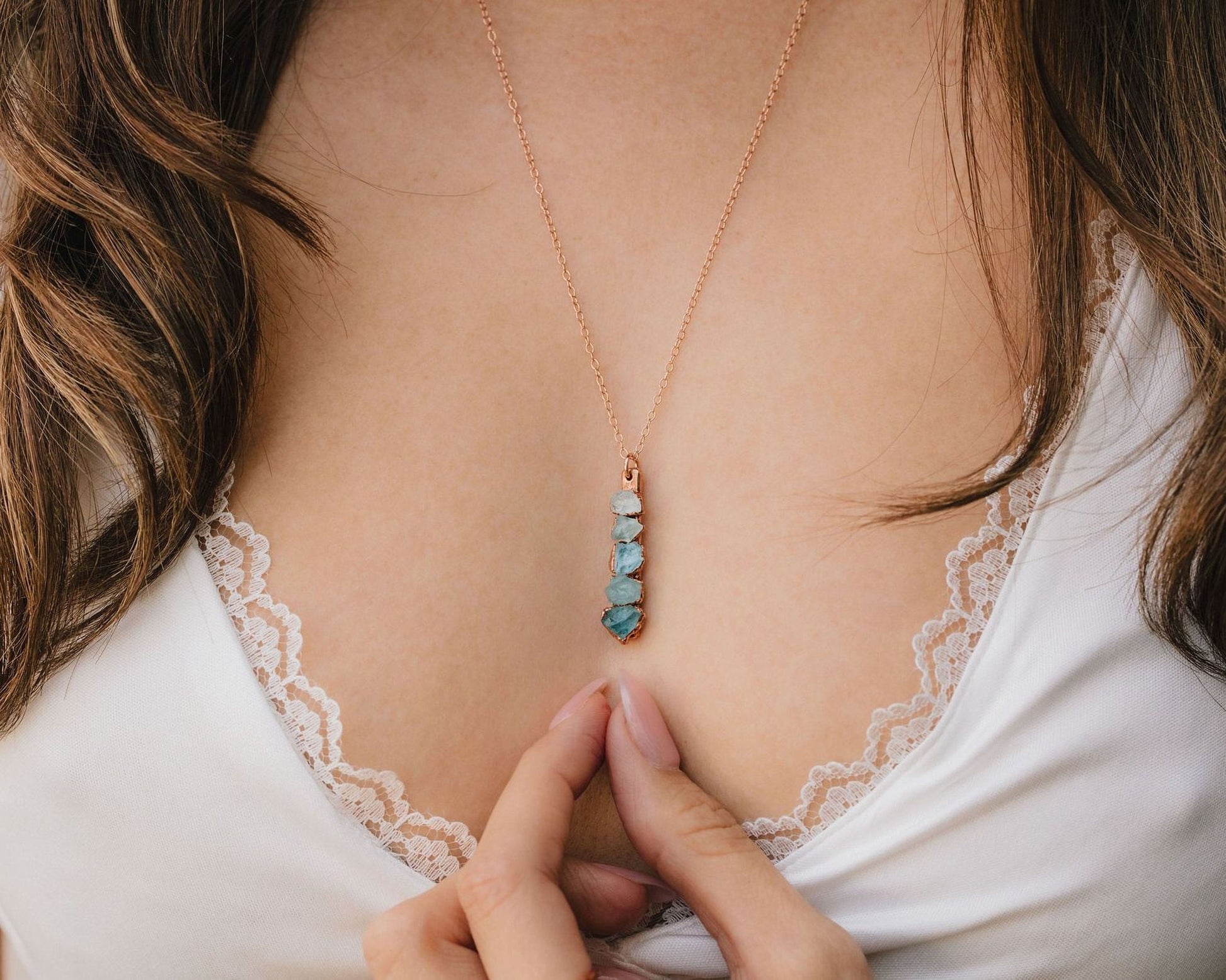 A close-up of a person's chest wearing a necklace with a pendant.