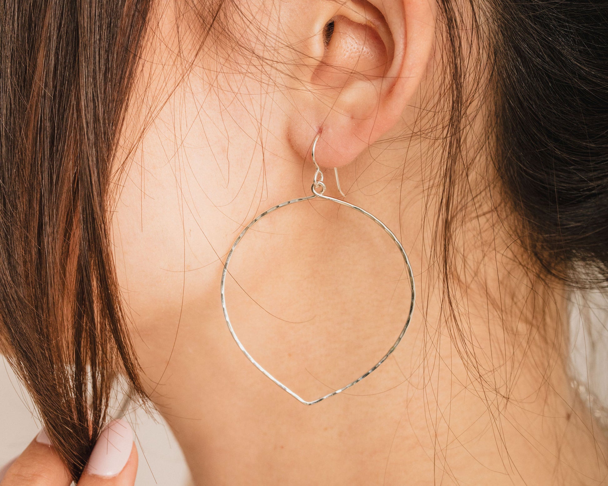 A close-up view of a person's ear adorned with a large, circular hoop earring.