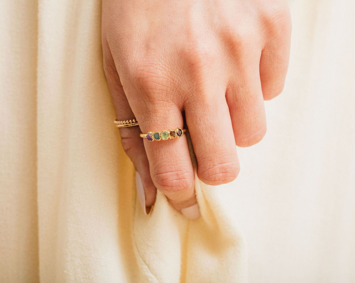 A close-up of a person's hand wearing a ring with a row of gemstones on the ring finger.