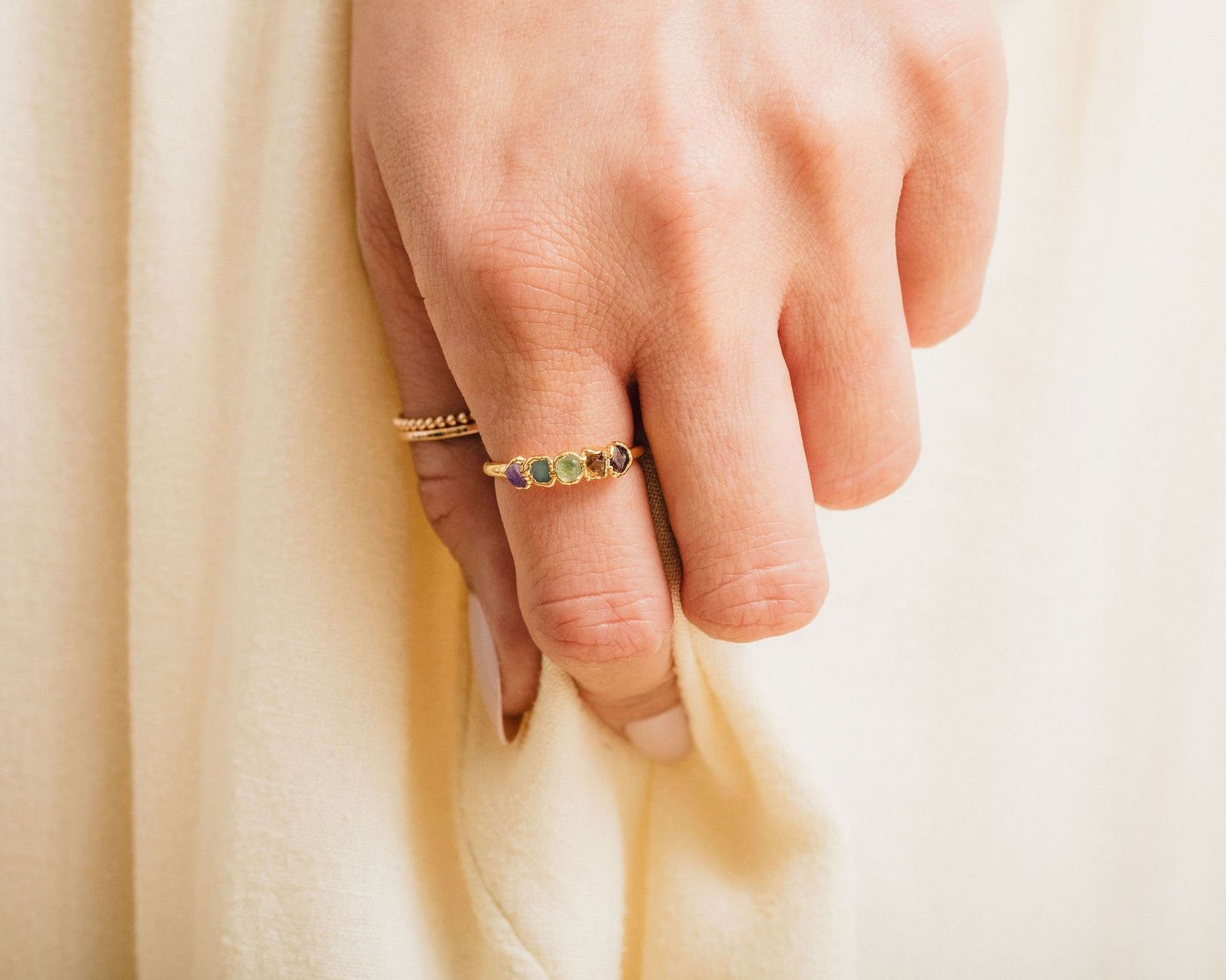 A close-up of a person's hand wearing a ring with a row of gemstones on the ring finger.