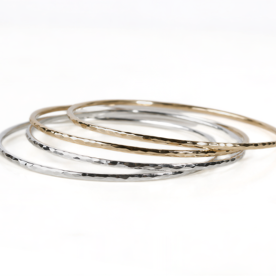 A stack of three silver and gold bangles on a white background.