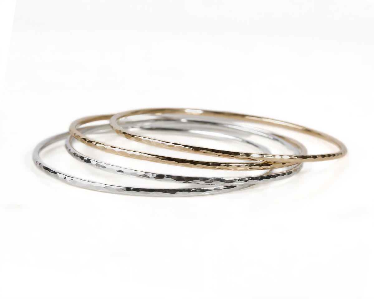 A stack of three silver and gold bangles on a white background.