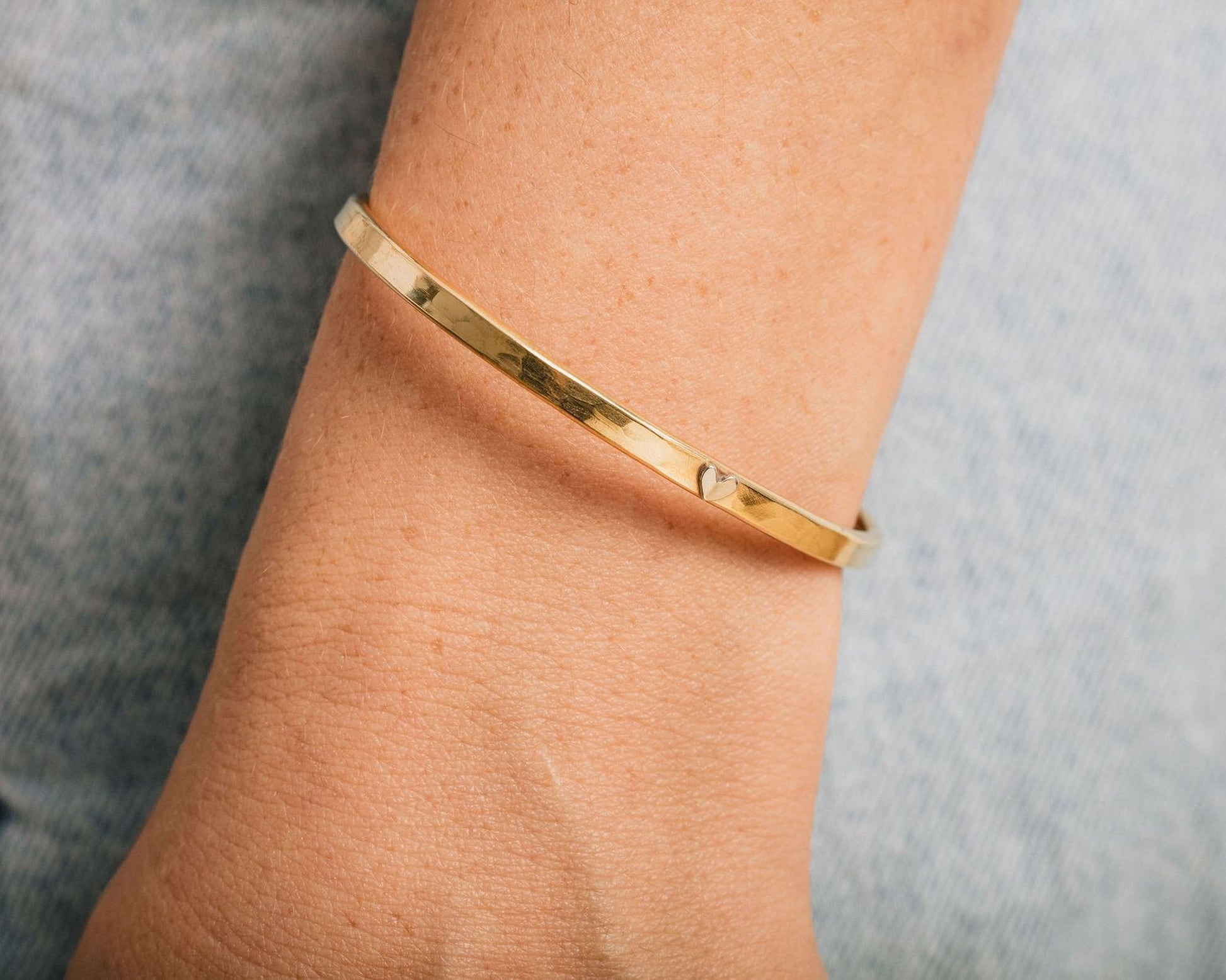 A gold-colored bracelet is worn on a person's wrist.