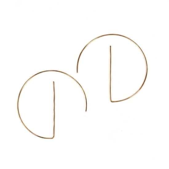 a pair of gold-colored earrings with a unique design, featuring a thin wire or rod that curves around the earlobe.