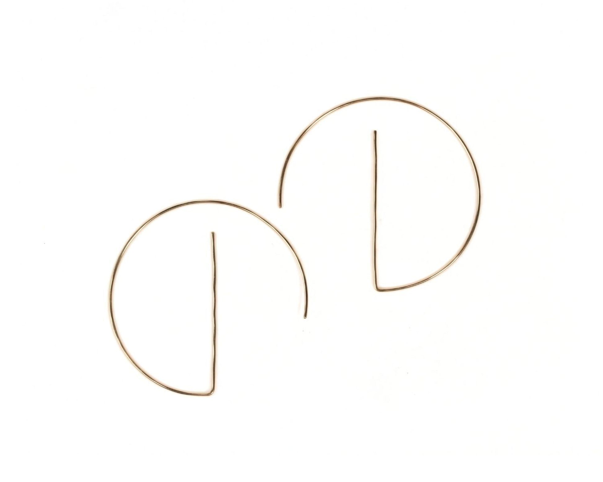 a pair of gold-colored earrings with a unique design, featuring a thin wire or rod that curves around the earlobe.
