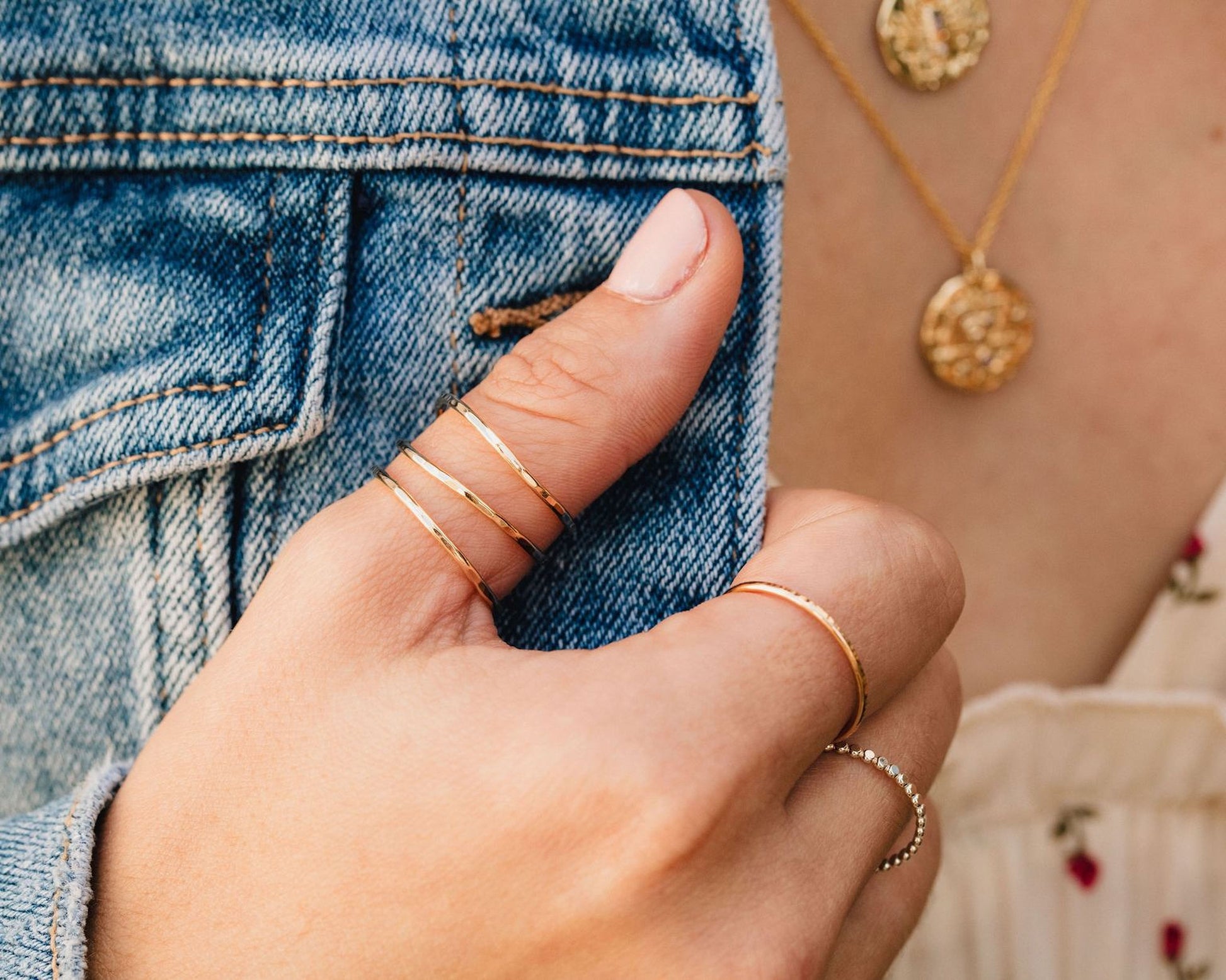 A close-up of a person's hand wearing multiple rings on their fingers, including a ring on the thumb and another ring on the ring finger.