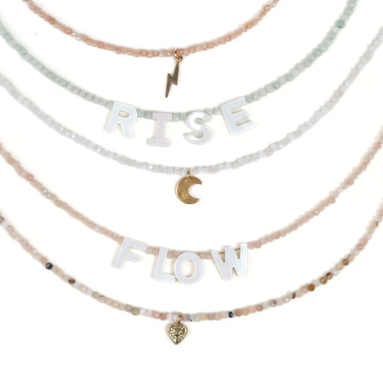 A necklace with the words "RISE FLOW" spelled out in large letters, along with a small heart charm.