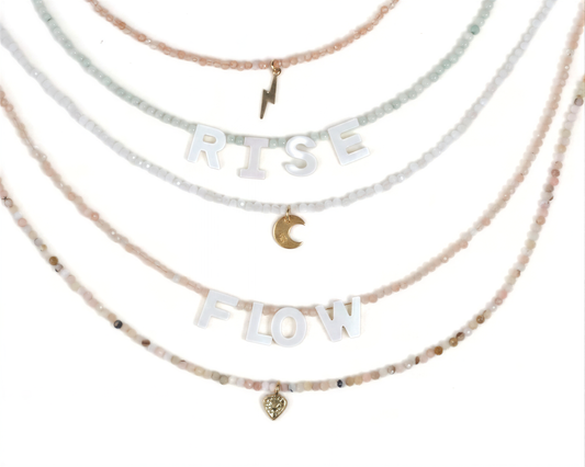 A necklace with the words "RISE FLOW" spelled out in large letters, along with a small heart charm.