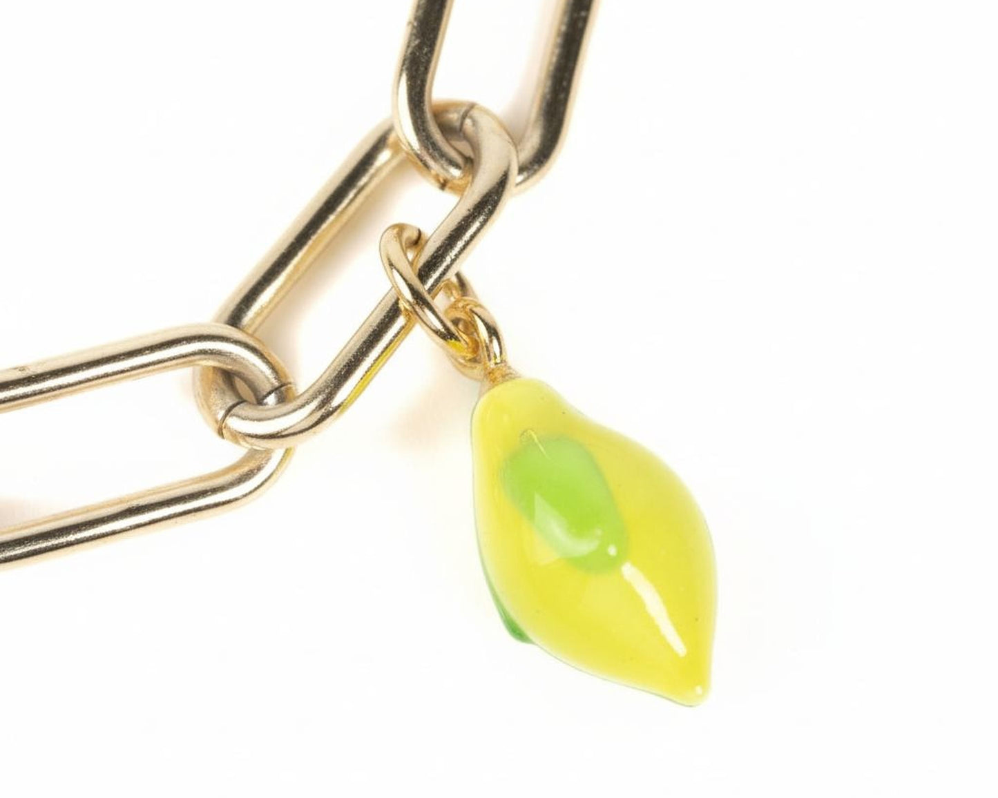 A close-up view of a gold-colored chain with a small yellow and green glass charm hanging from it.