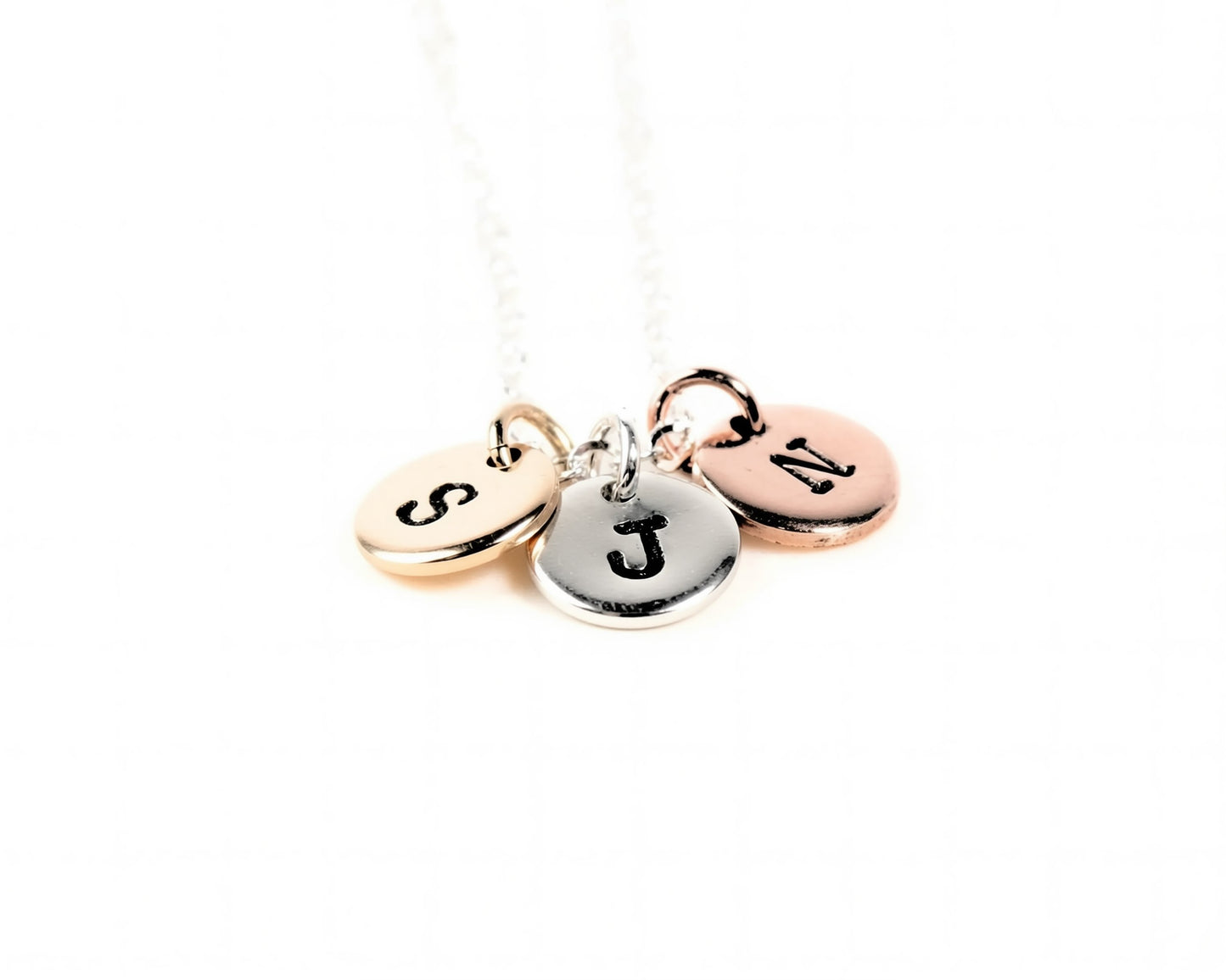 A necklace with three round charms attached to it, each with a letter engraved on it.