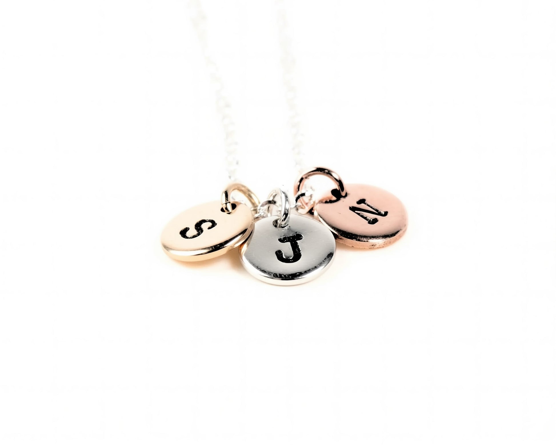 A necklace with three round charms attached to it, each with a letter engraved on it.