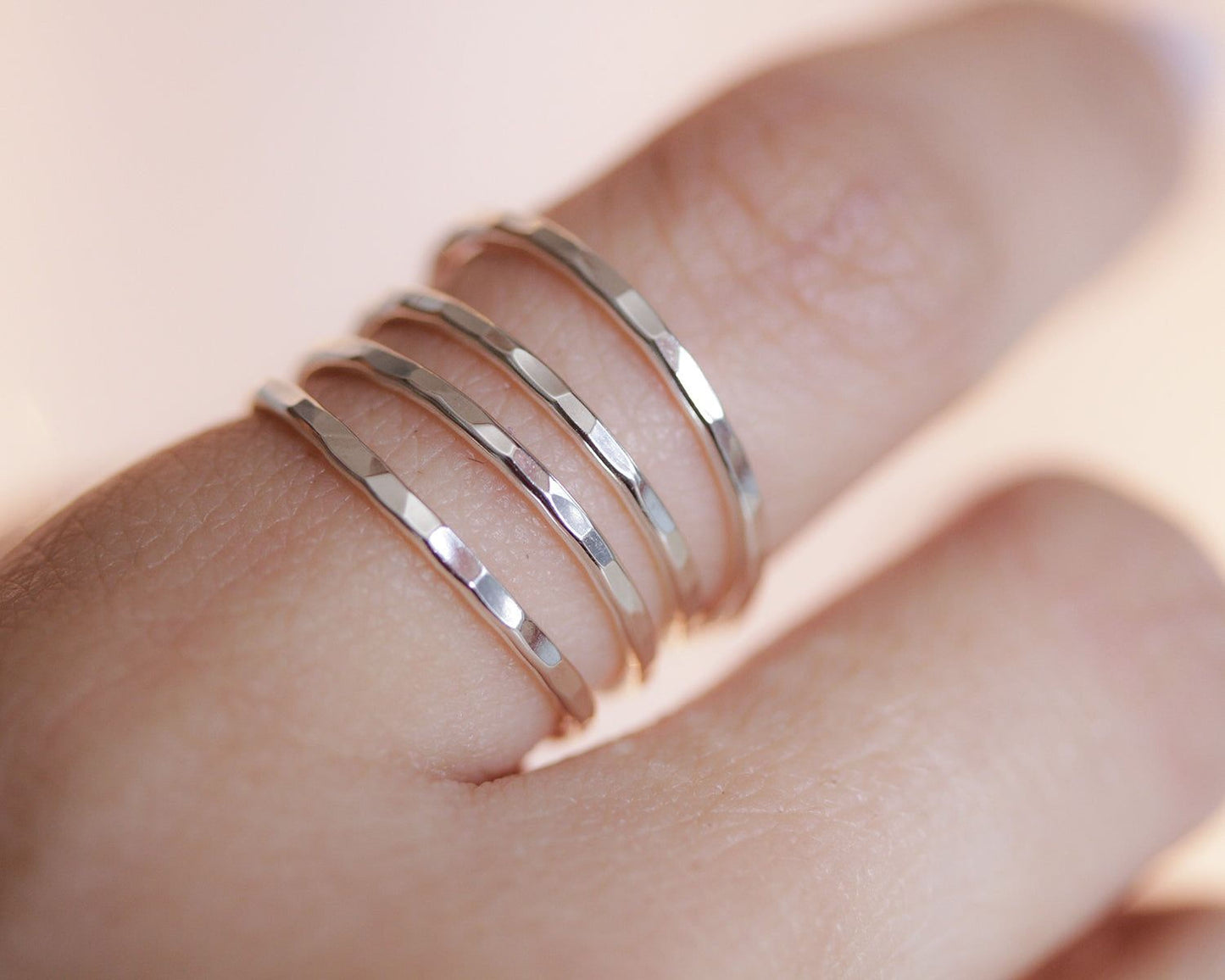 A close-up view of a person's hand wearing three stacked silver rings on the ring finger.