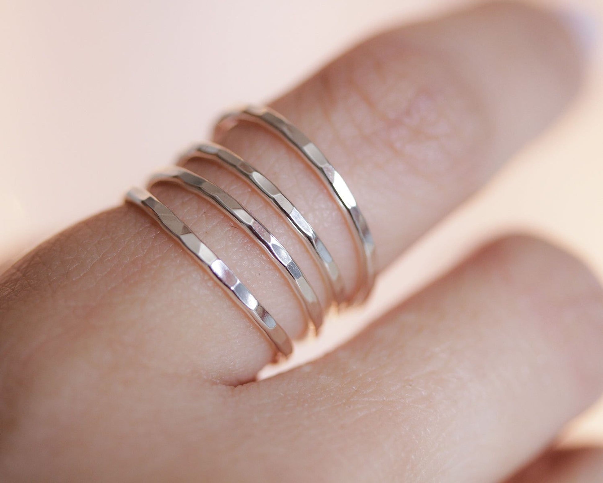 A close-up view of a person's hand wearing three stacked silver rings on the ring finger.
