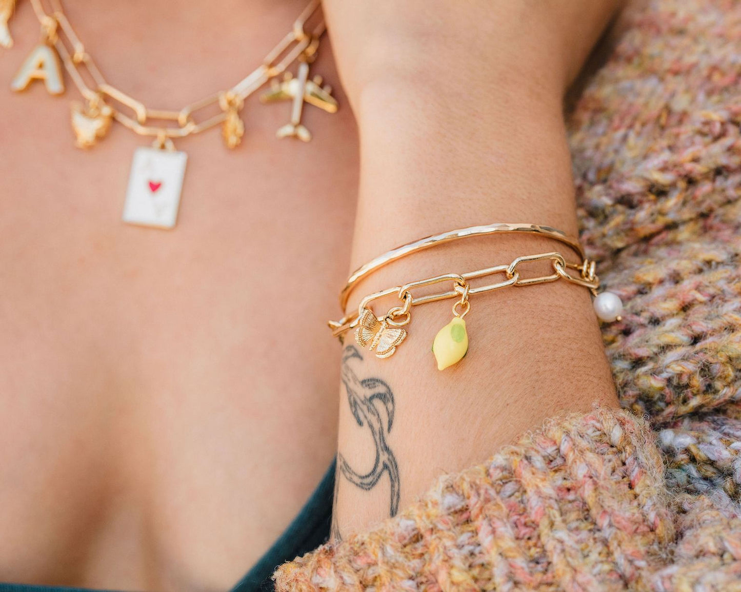 A close-up view of a person's arm adorned with multiple gold-colored bracelets and a necklace.