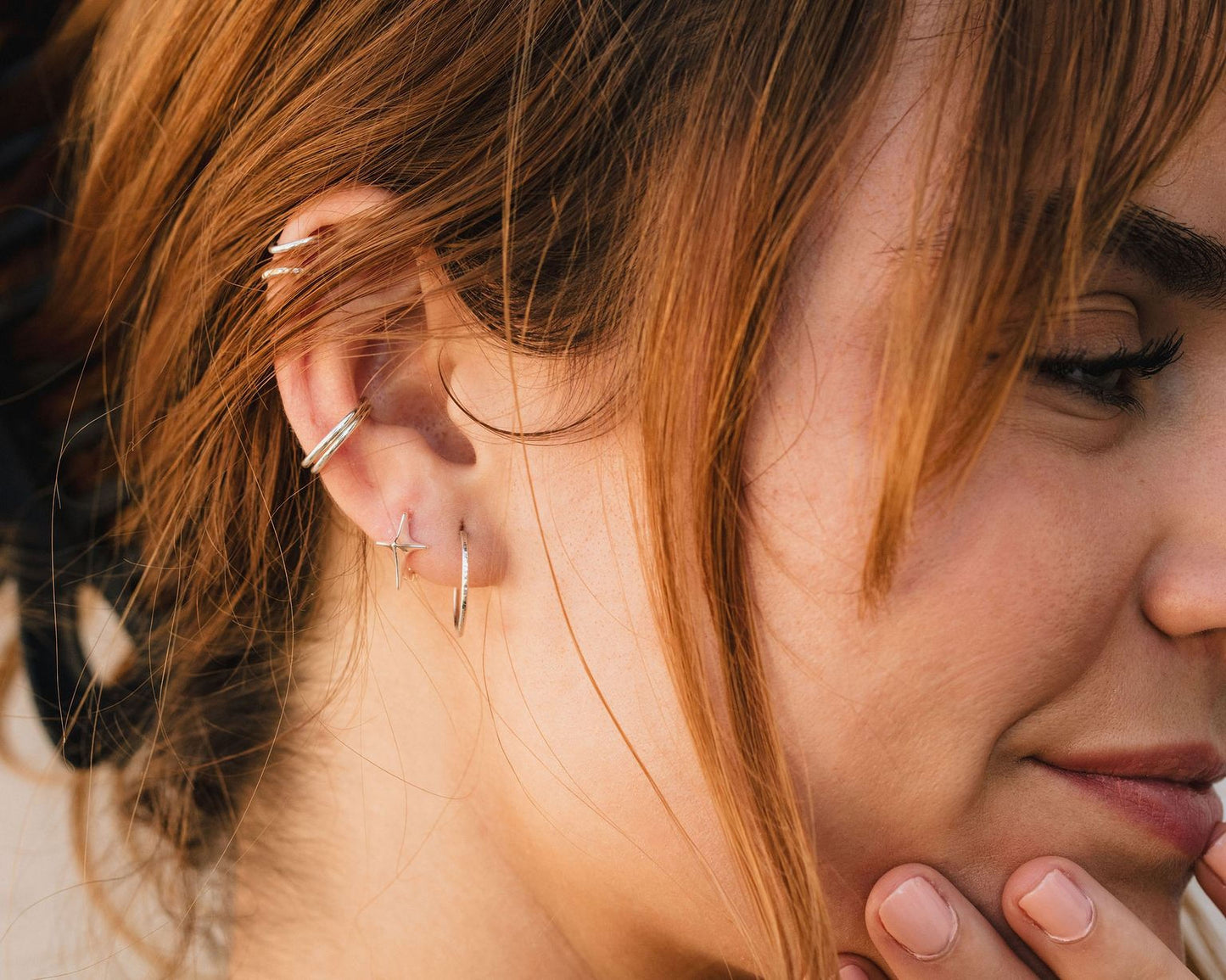A close-up of a person's face, focusing on their earrings and hair.