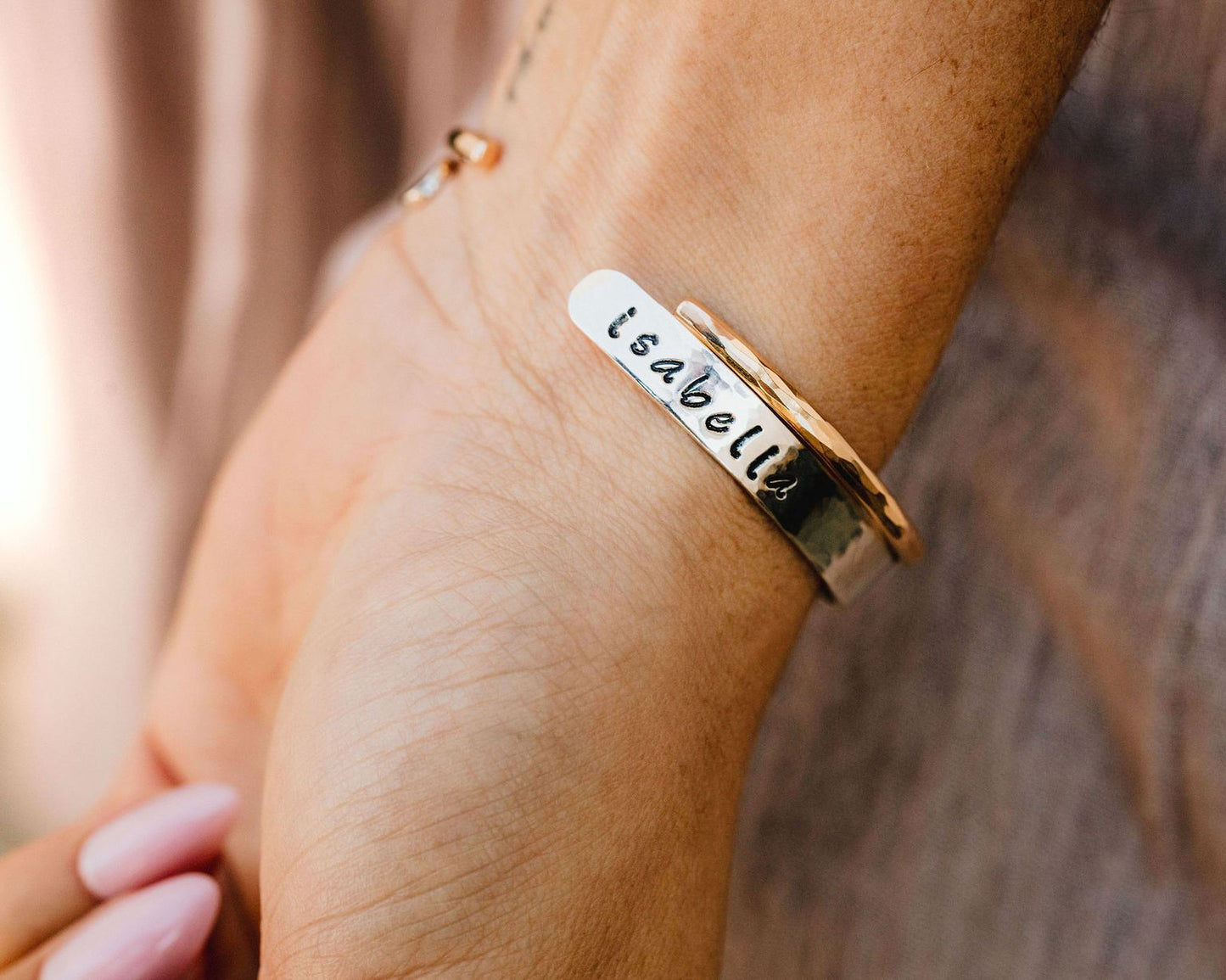 A close-up view of a person's wrist wearing a bracelet with the name "Isabella" engraved on it.