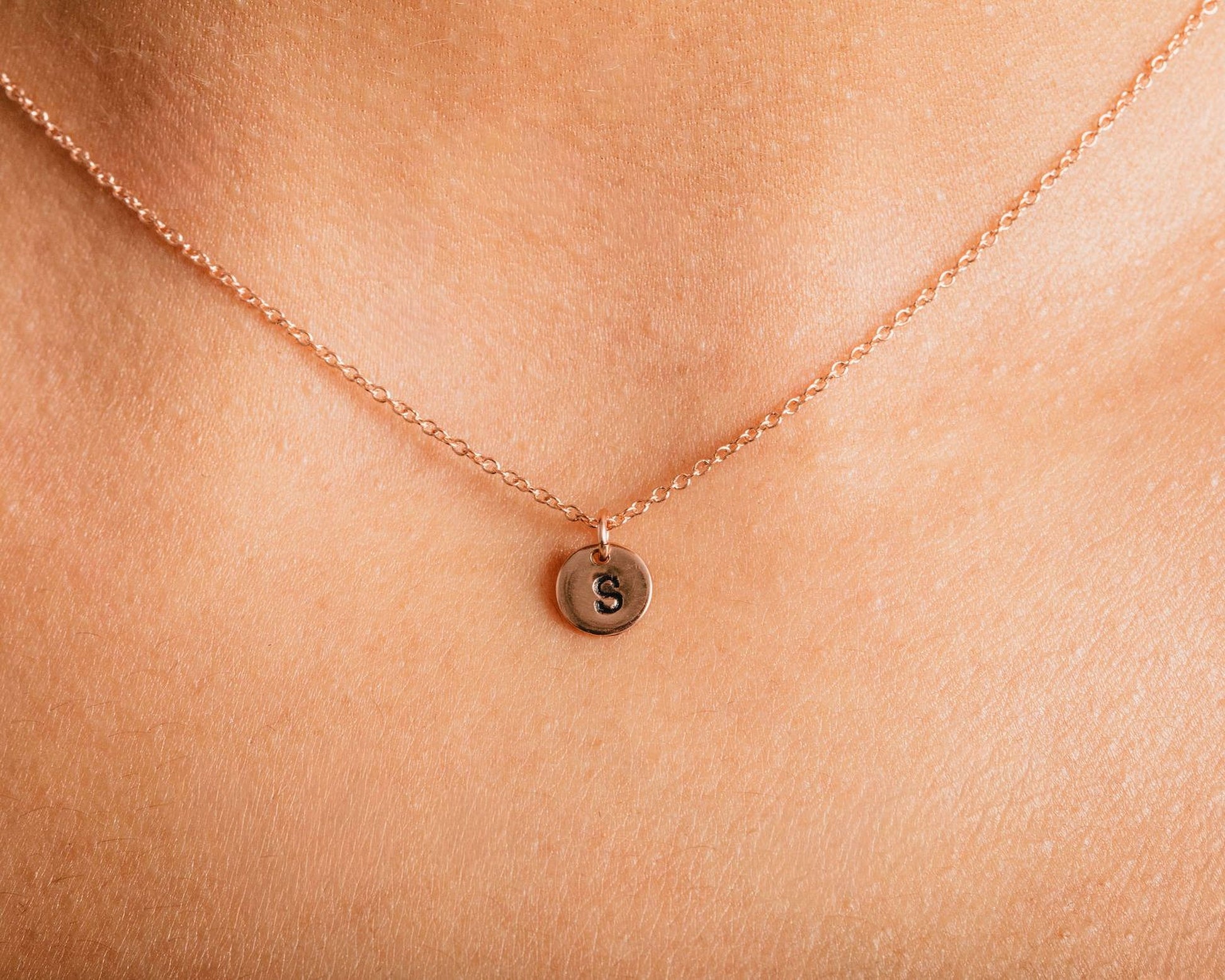 A delicate necklace with a small pendant featuring the letter 'S' on it.