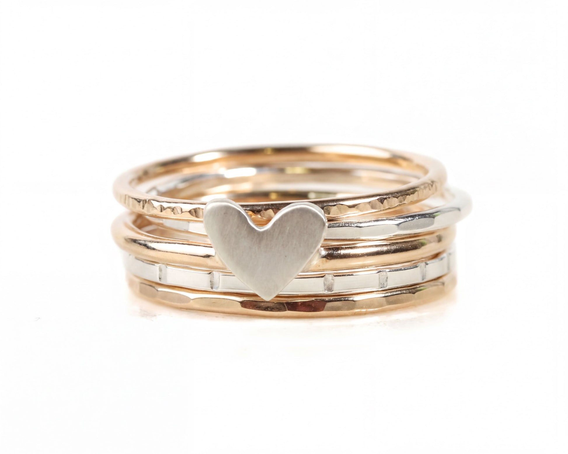 A stack of three rings, with the middle ring featuring a heart-shaped charm.