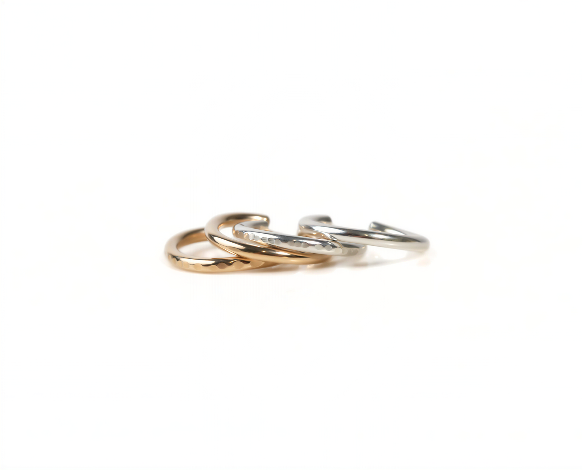 A close-up image of three rings of different colors - gold, silver, and bronze - arranged in a circular pattern against a white background.
