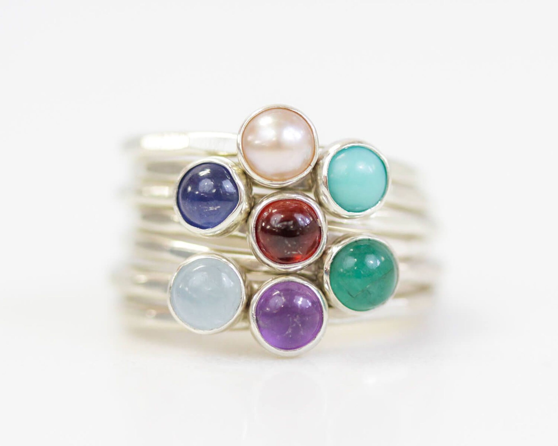 A stack of silver rings with colorful gemstones on top.