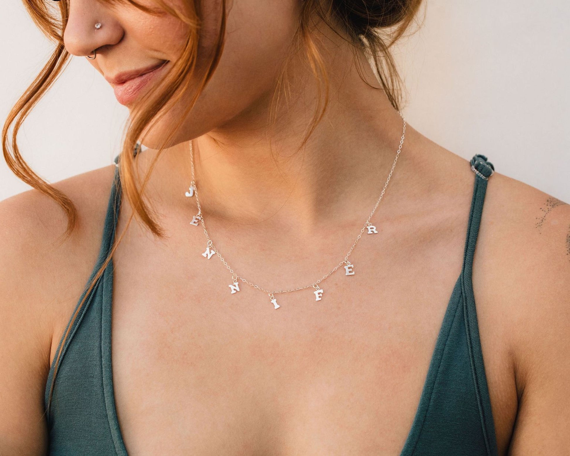 A woman wearing a necklace with the name "JENNY" engraved on it.