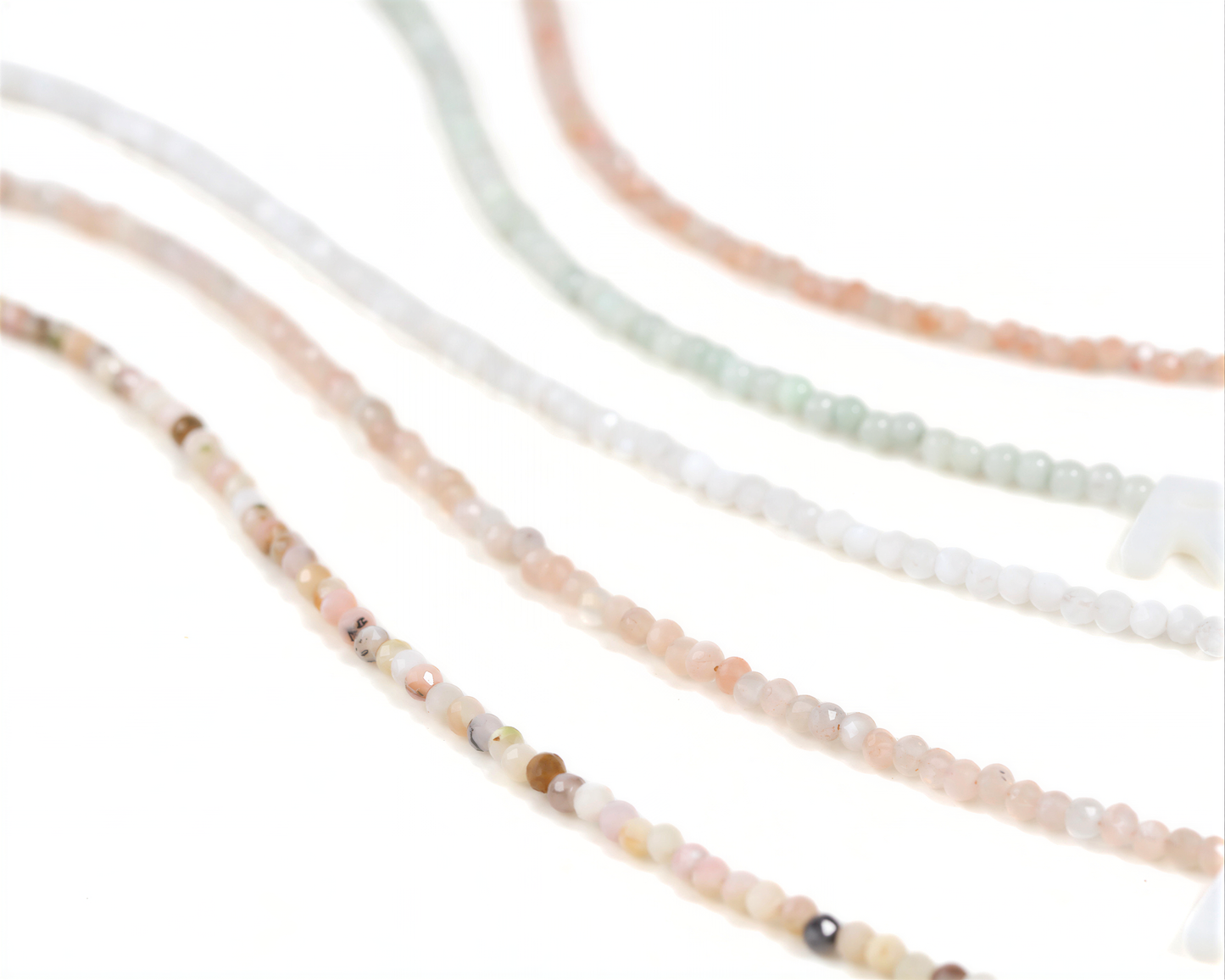 A collection of colorful beaded necklaces or bracelets, with various shades of pink, white, and green beads arranged in a wavy pattern.