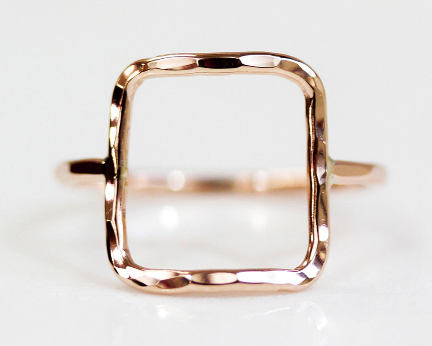 A simple, square-shaped gold ring with a textured, hand-forged design.