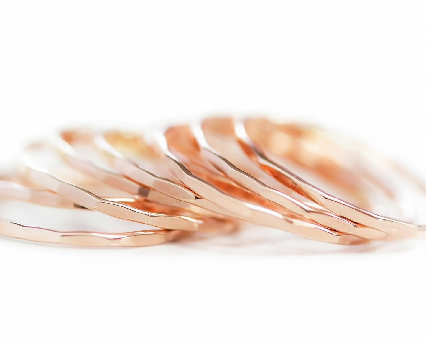 A close-up image of a collection of thin, metallic rings or bracelets arranged in a row.