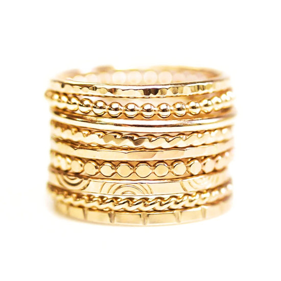 A stack of gold-colored rings with various designs and patterns.