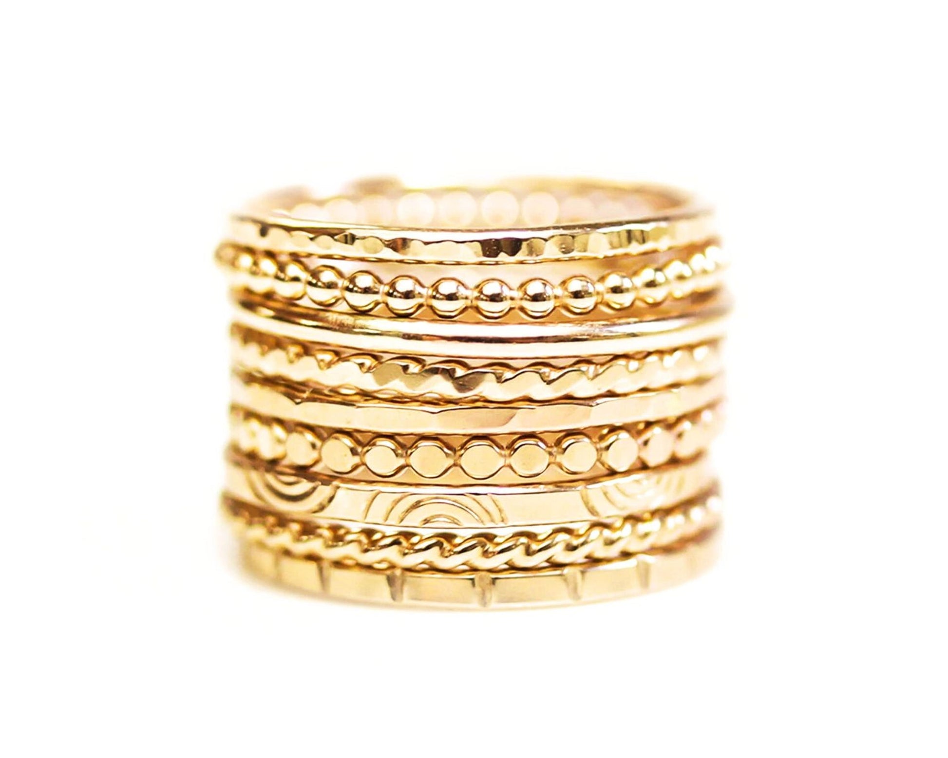 A stack of gold-colored rings with various designs and patterns.