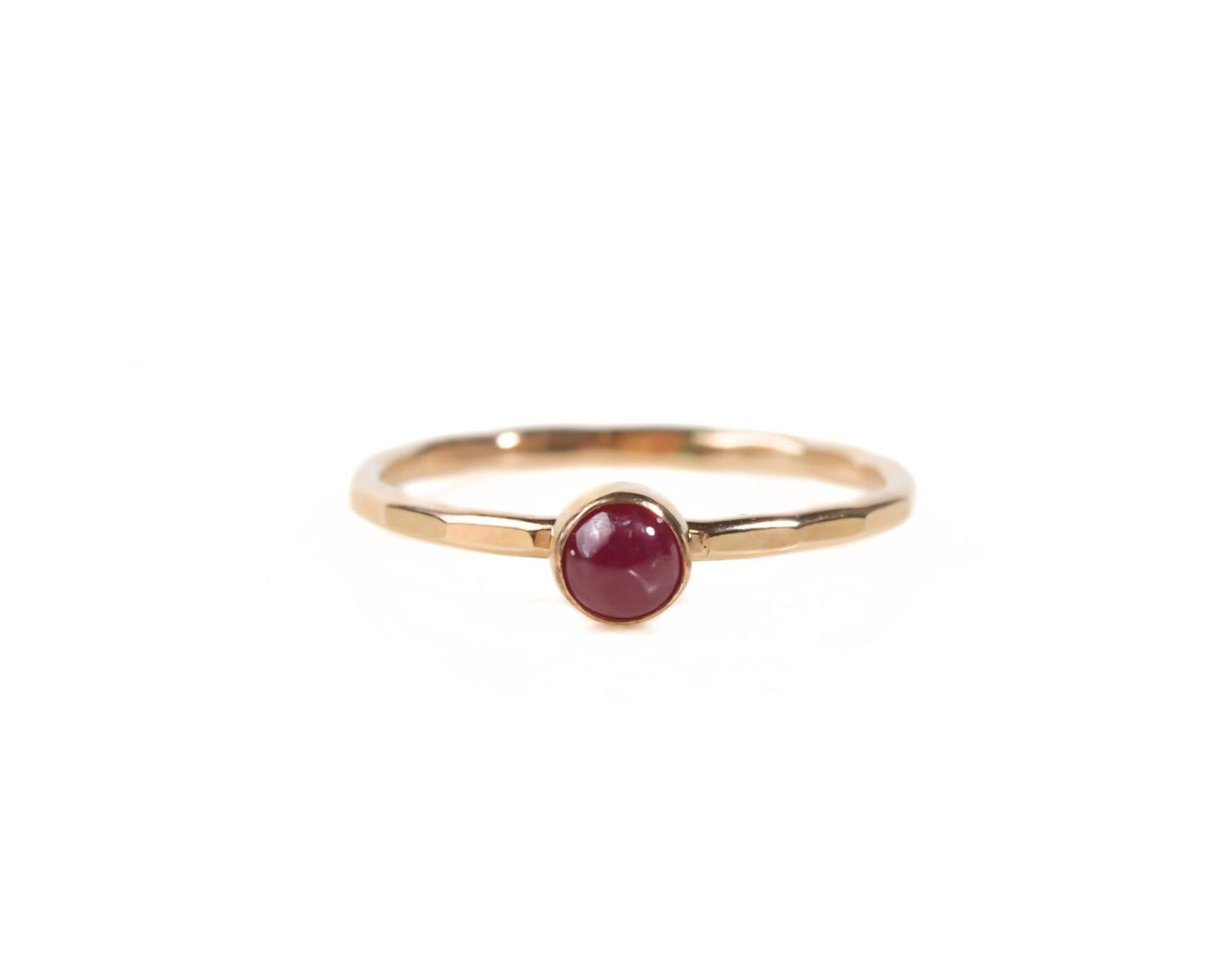 A gold ring with a red gemstone, likely a ruby, set in the center.