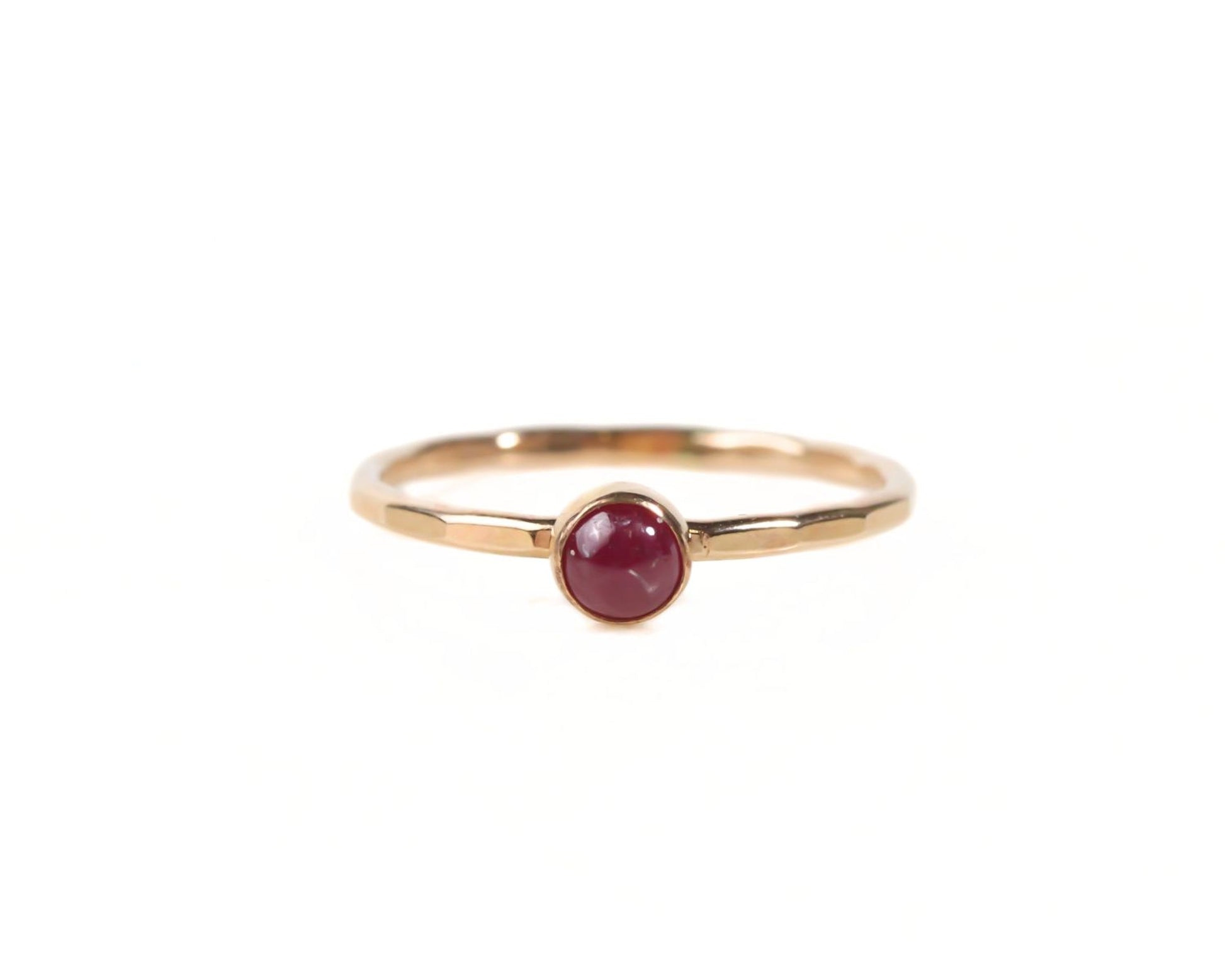 A gold ring with a red gemstone, likely a ruby, set in the center.
