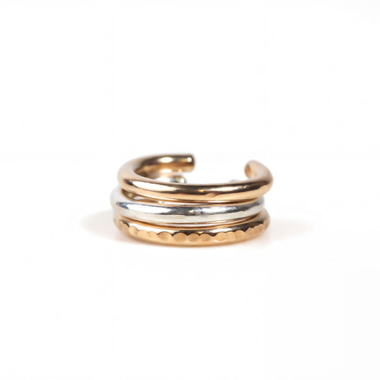 A gold and silver earring with a curved design, resting on a white background.