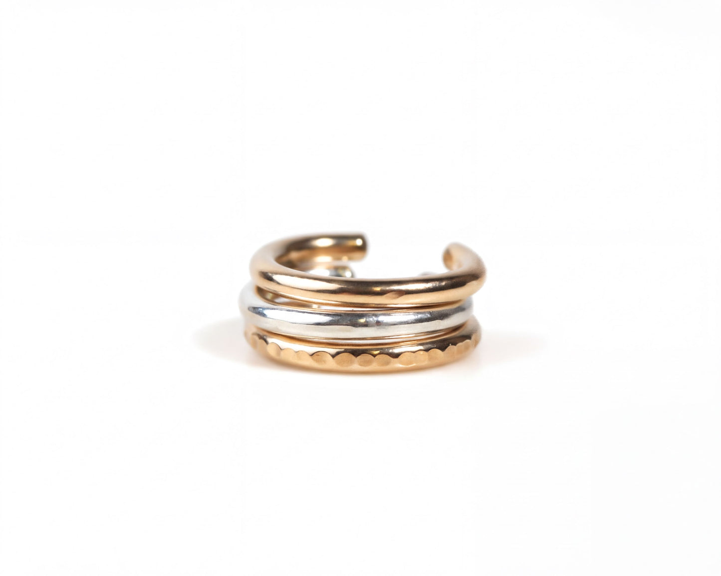 A gold and silver earring with a curved design, resting on a white background.
