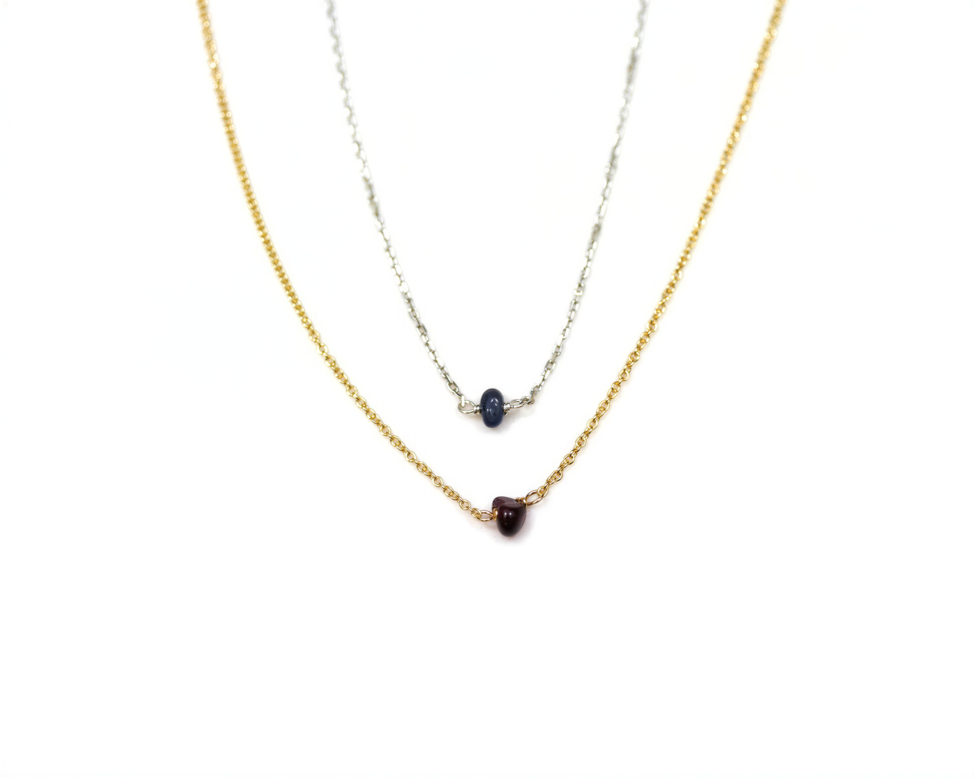 A necklace with two pendants, one in gold and one in blue, against a white background.