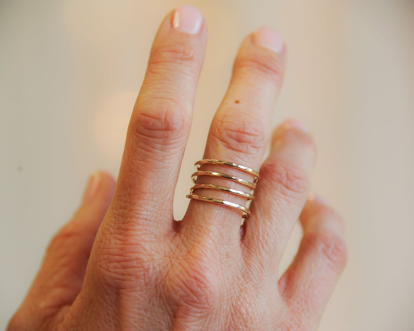 A close-up view of a person's hand wearing a gold ring with multiple concentric rings.