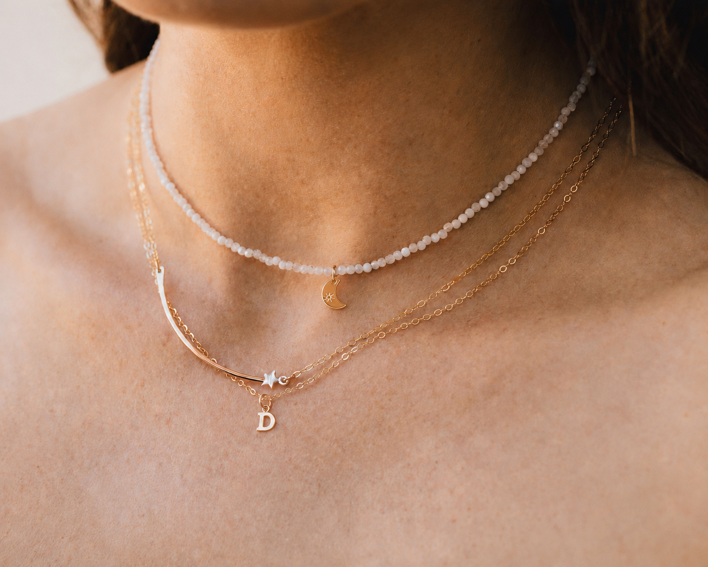 A close-up view of a person's neck adorned with multiple necklaces, including a beaded necklace and a pendant necklace.
