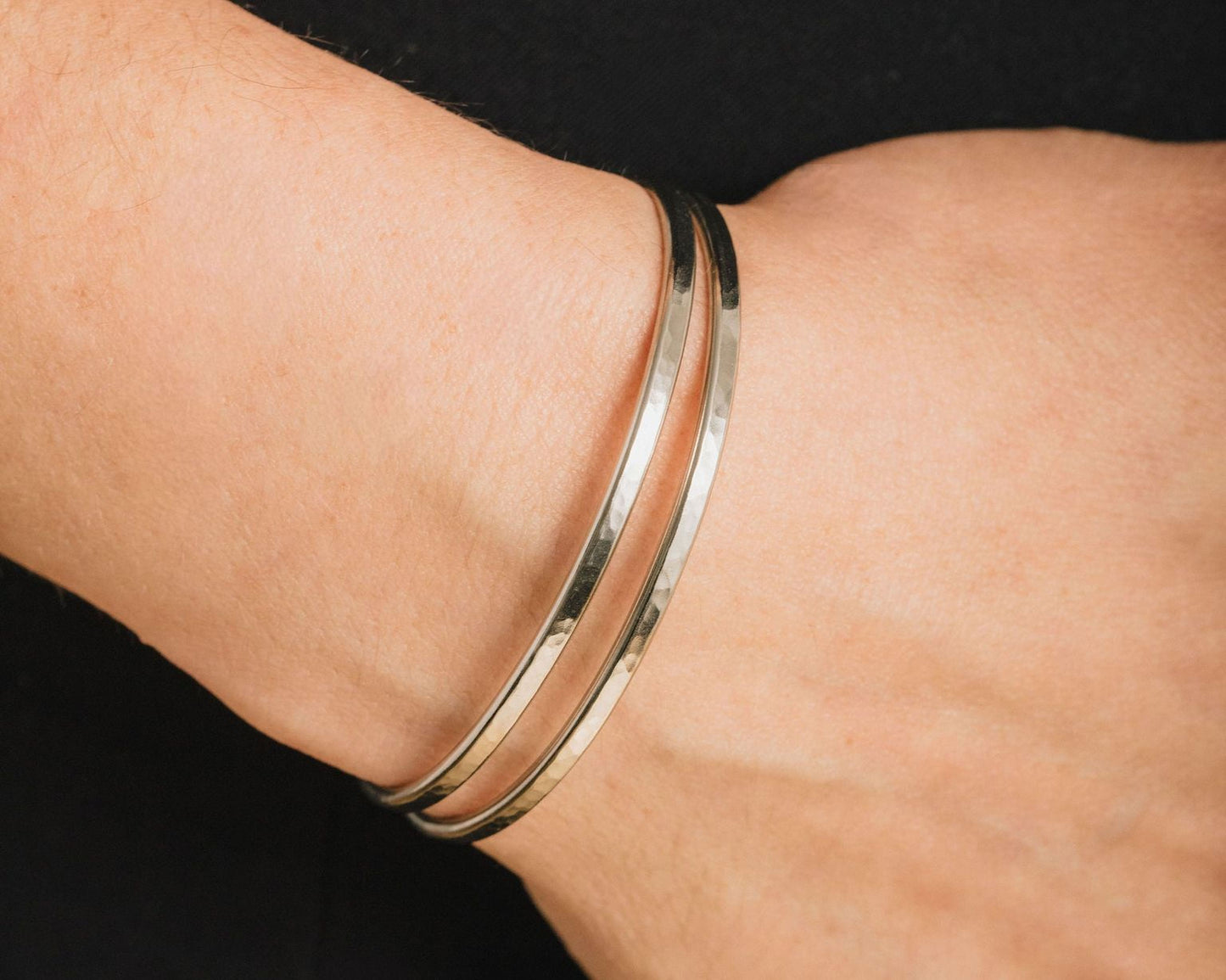A close-up view of a person's wrist wearing a silver bracelet.