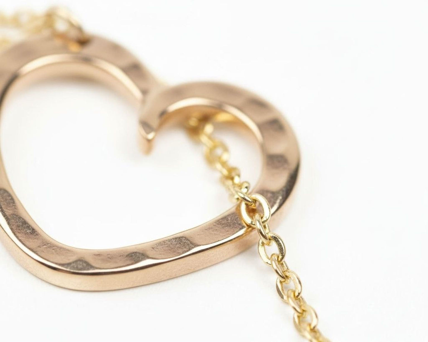 A close-up image of a gold-colored heart-shaped pendant with a chain attached to it.