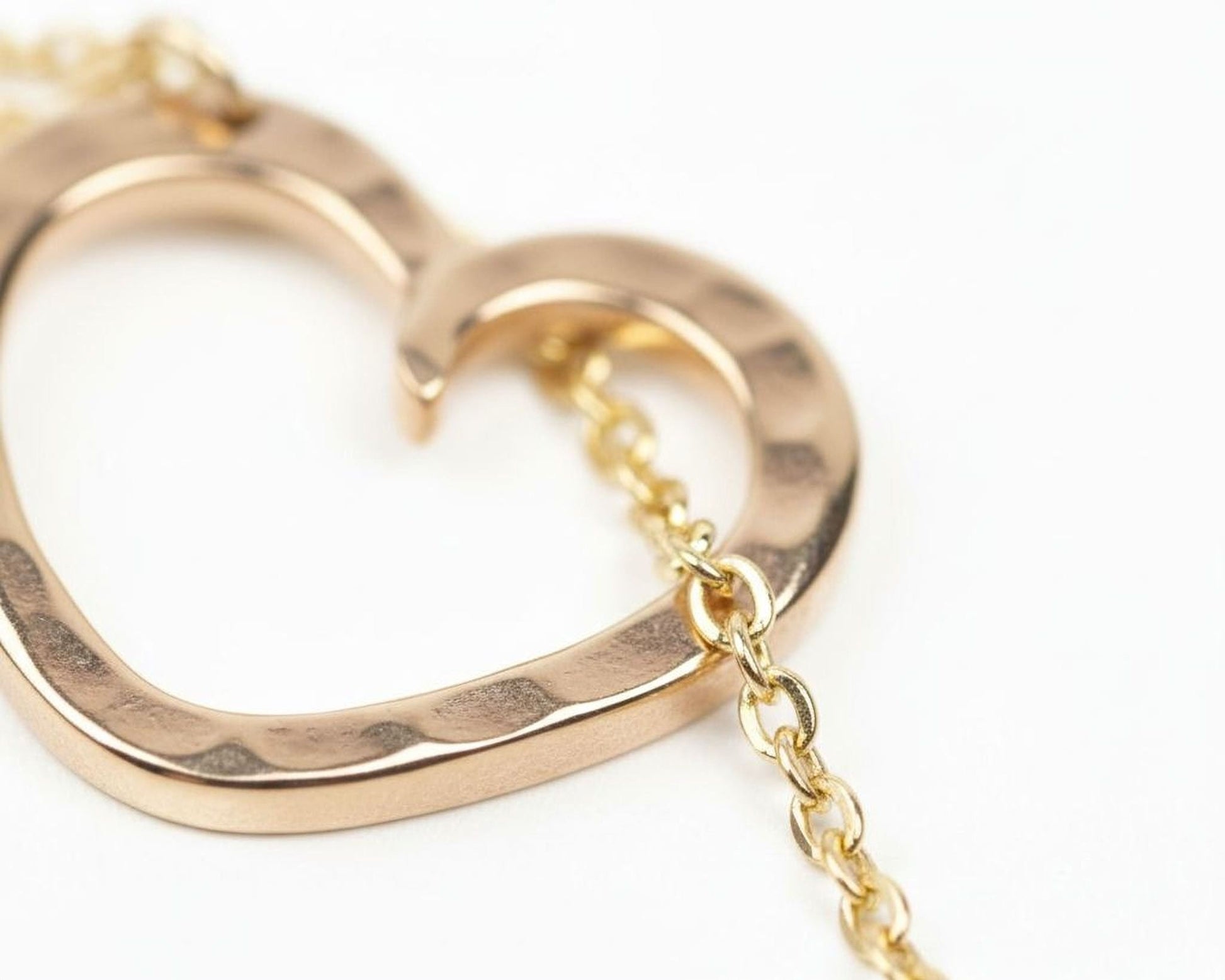 A close-up image of a gold-colored heart-shaped pendant with a chain attached to it.