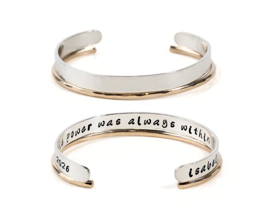 two silver bracelets with engraved text on them.