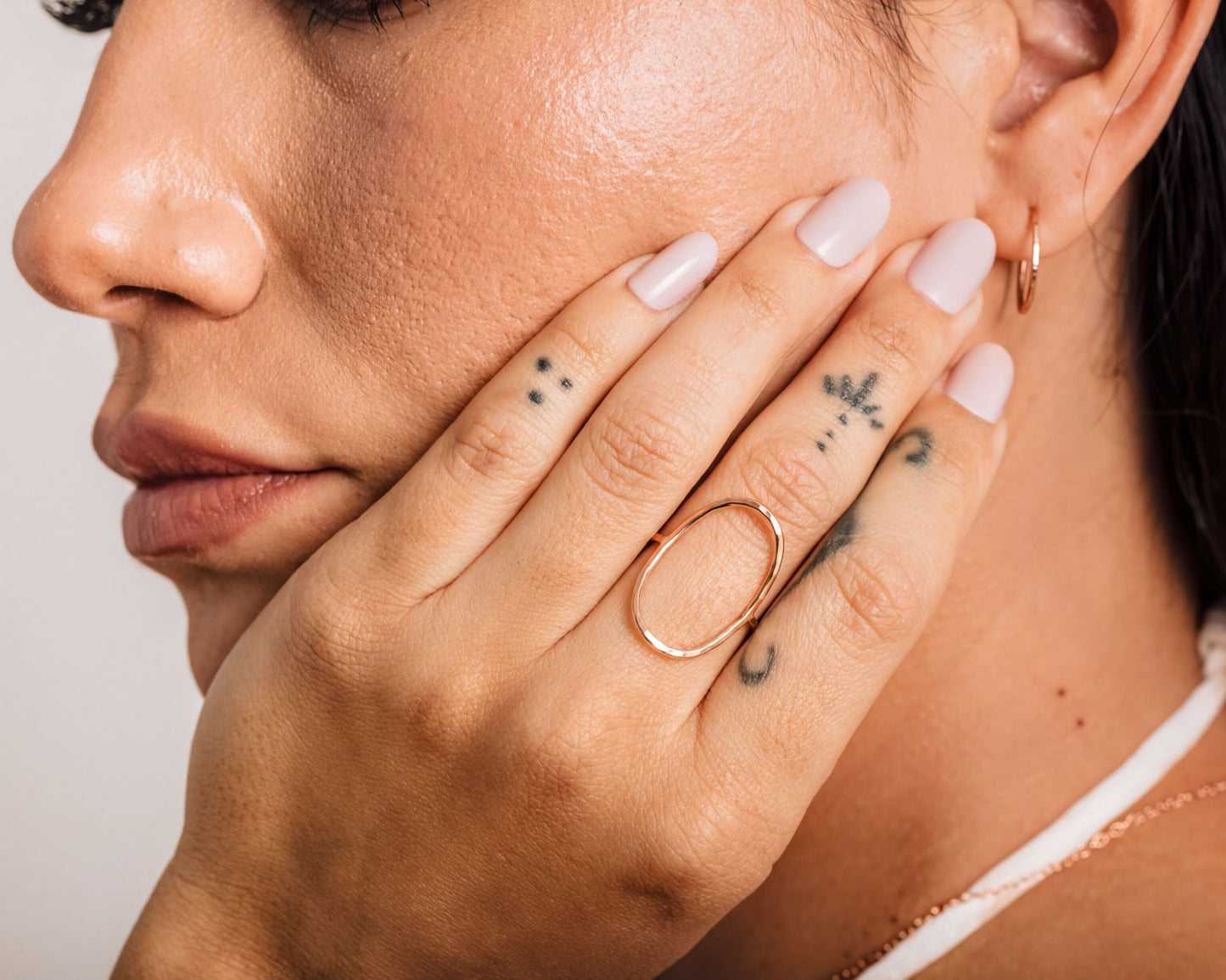 A close-up of a person's hand with a ring on it, and tattoos on the fingers.